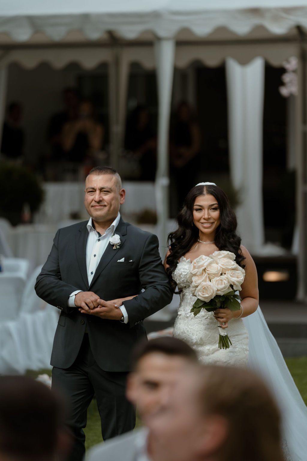 A happy couple in formal wedding attire sharing joyful moments during an outdoor wedding celebration.