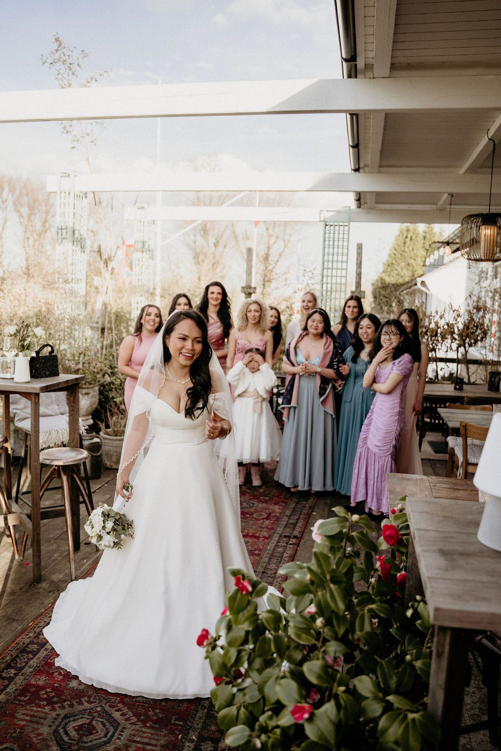 Wedding party poses together in an indoor venue with rustic decor, vintage rugs, and floral arrangements.