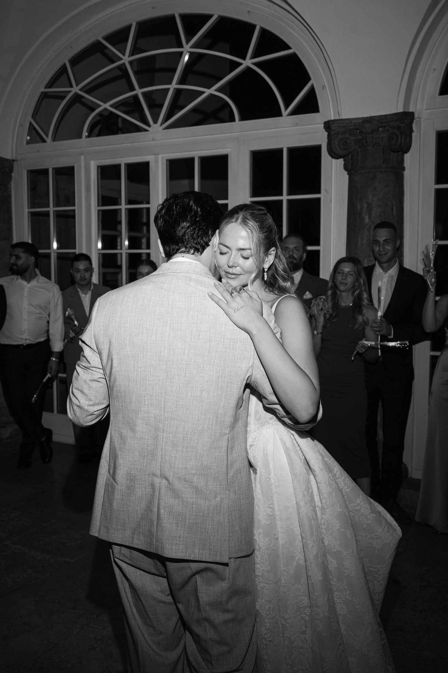 Bride and groom share emotional first dance in black and white photo at elegant wedding reception.