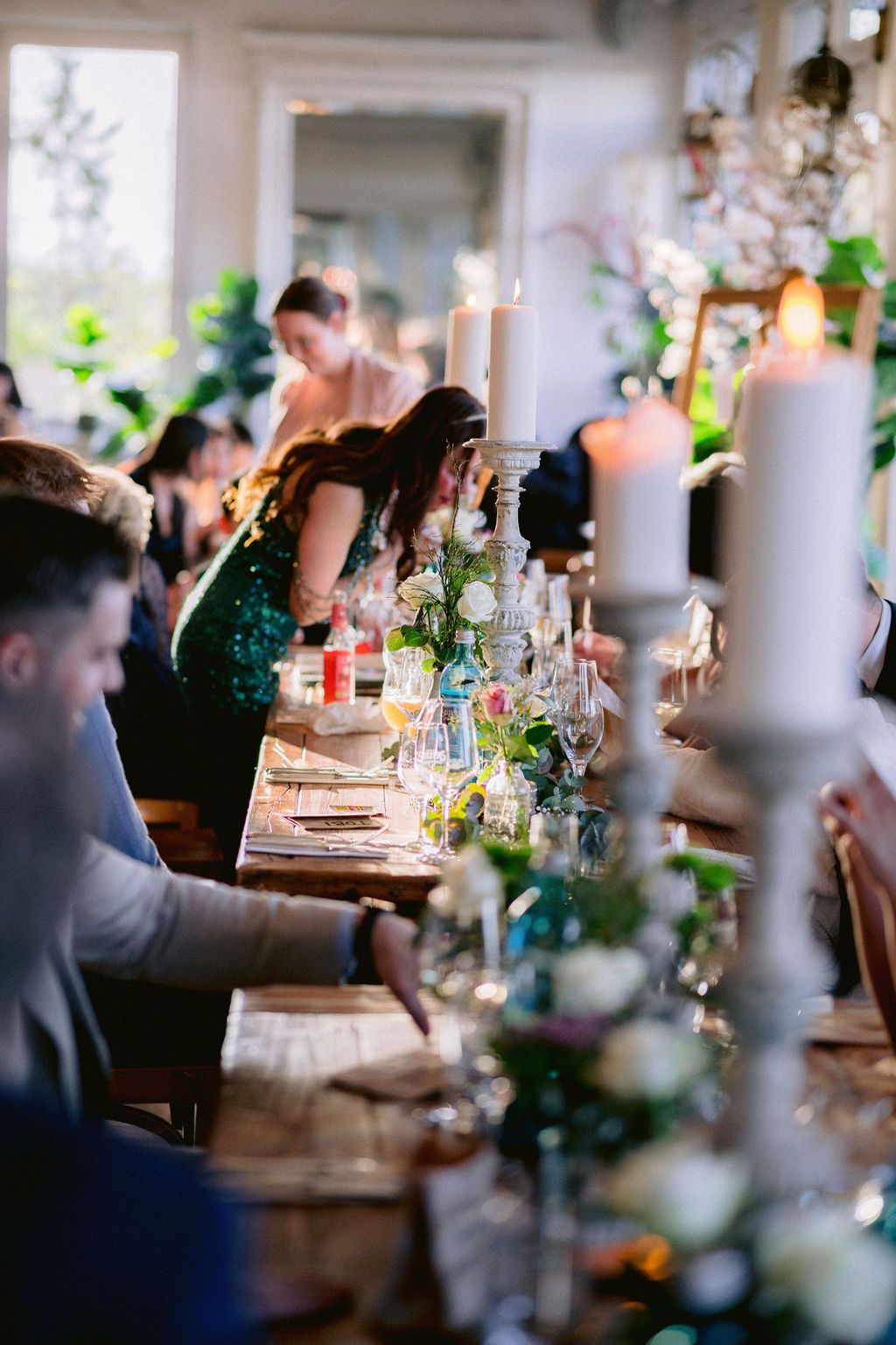 Guests seated at elegant dining tables with glowing candles and floral arrangements at an intimate restaurant event.