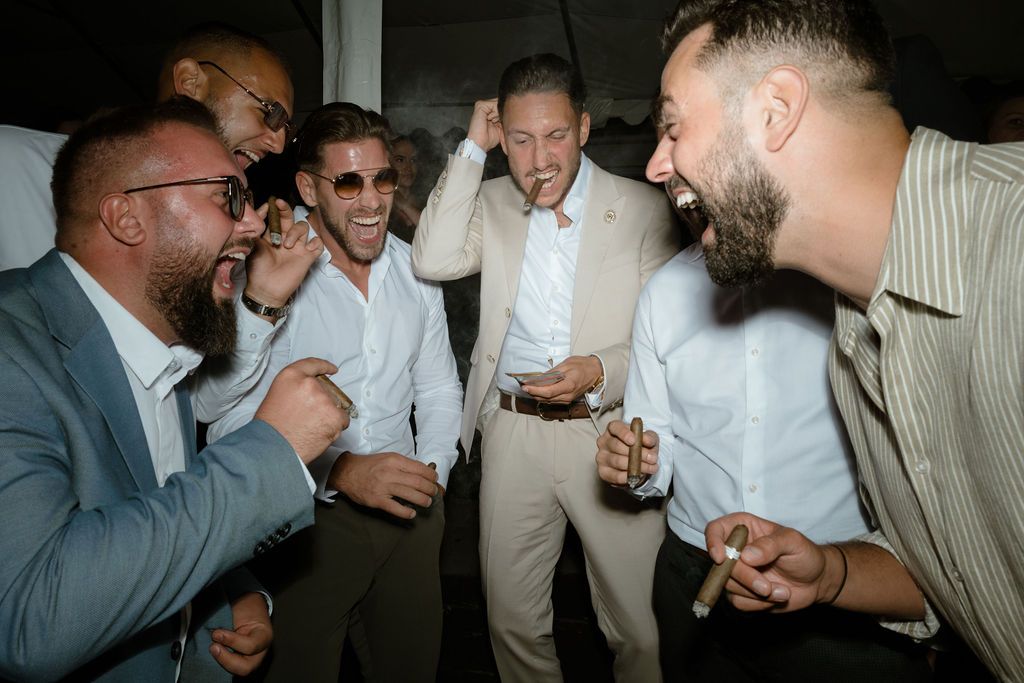 A group laughing and sharing drinks in a lively indoor nighttime setting with dramatic lighting.