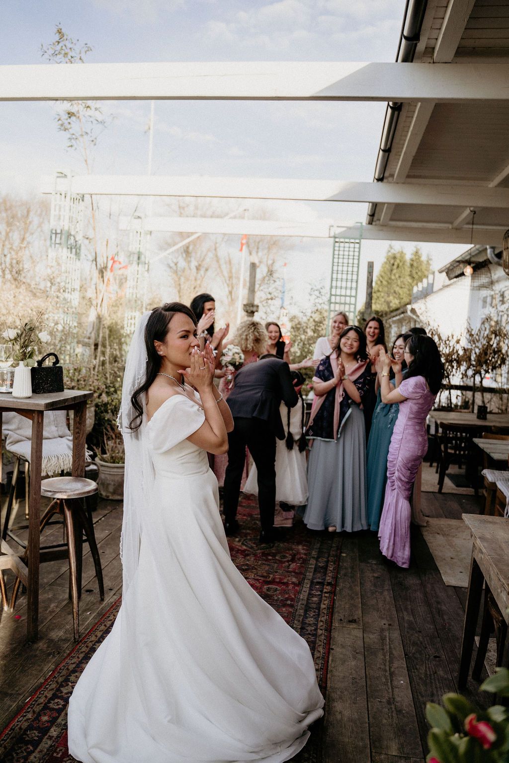 A wedding celebration on an outdoor deck with guests in formal attire gathering for a special moment.