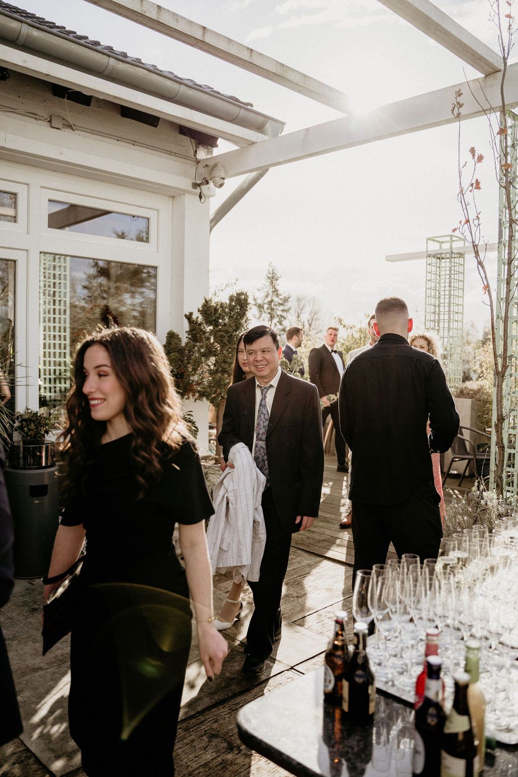 Event attendees mingle on an outdoor patio with drinks and decor during a formal gathering at sunset.