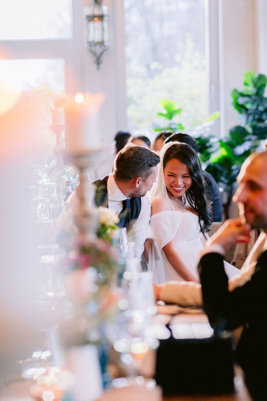 A joyous wedding reception scene with guests gathered at decorated tables in an elegant indoor venue.