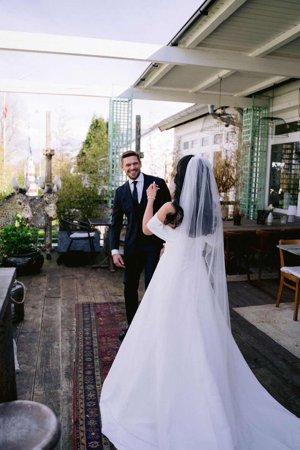 A couple dancing and twirling in their wedding attire on a rustic patio with elegant columns and greenery in the background.