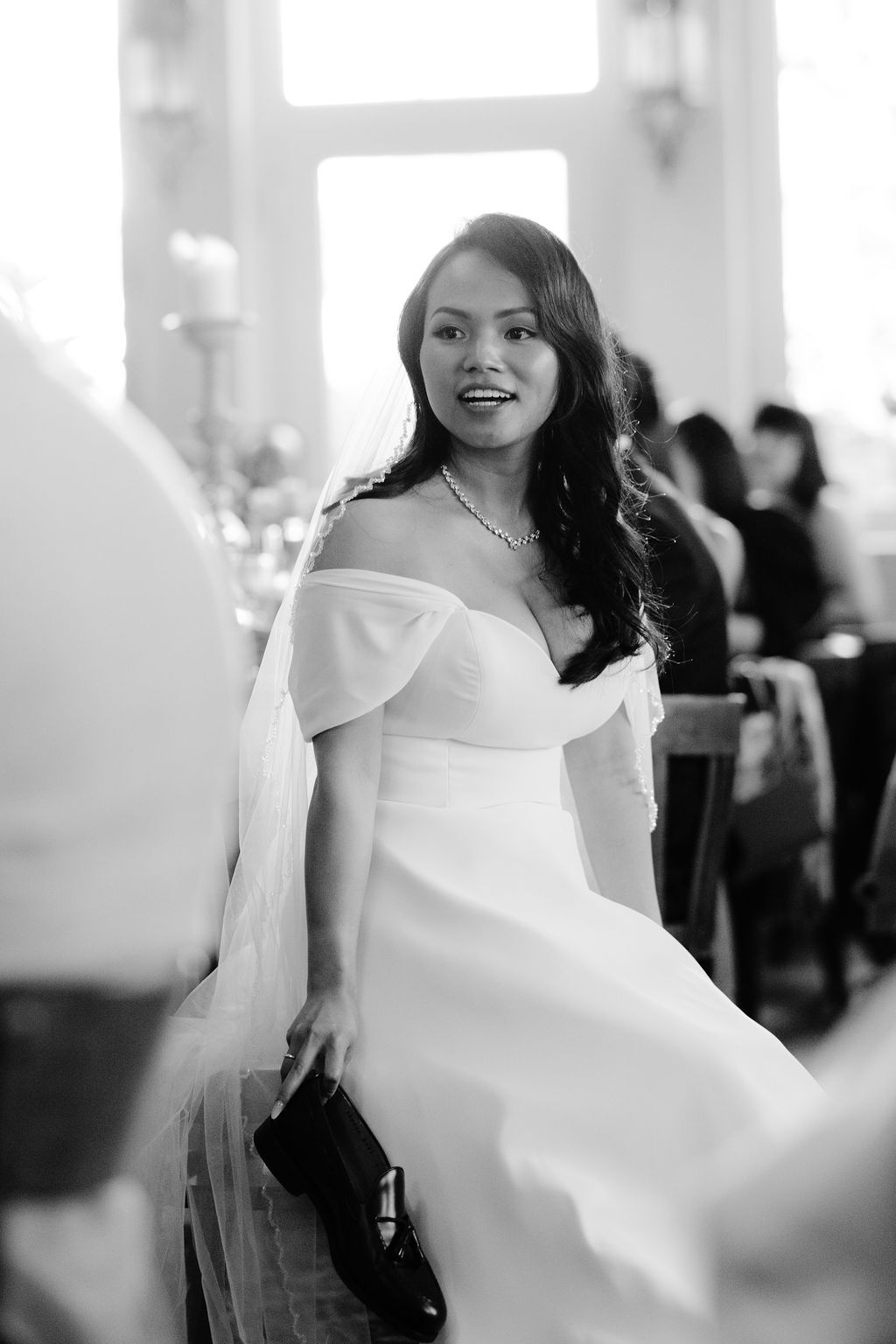 A bride in a white wedding dress twirls and smiles with motion blur during a wedding reception celebration.