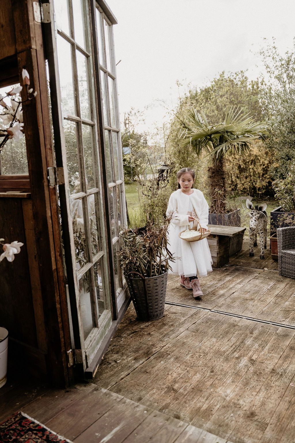 A rustic wood-floored conservatory with large windows and potted plants provides a bright, airy setting for capturing moments.