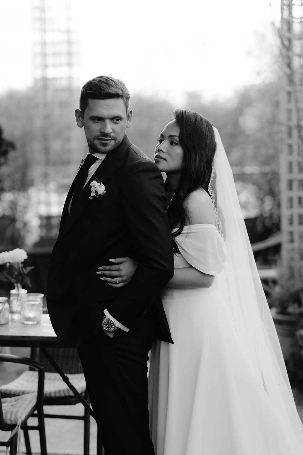 A romantic newlywed couple embraces in a series of black and white wedding photos captured outdoors.