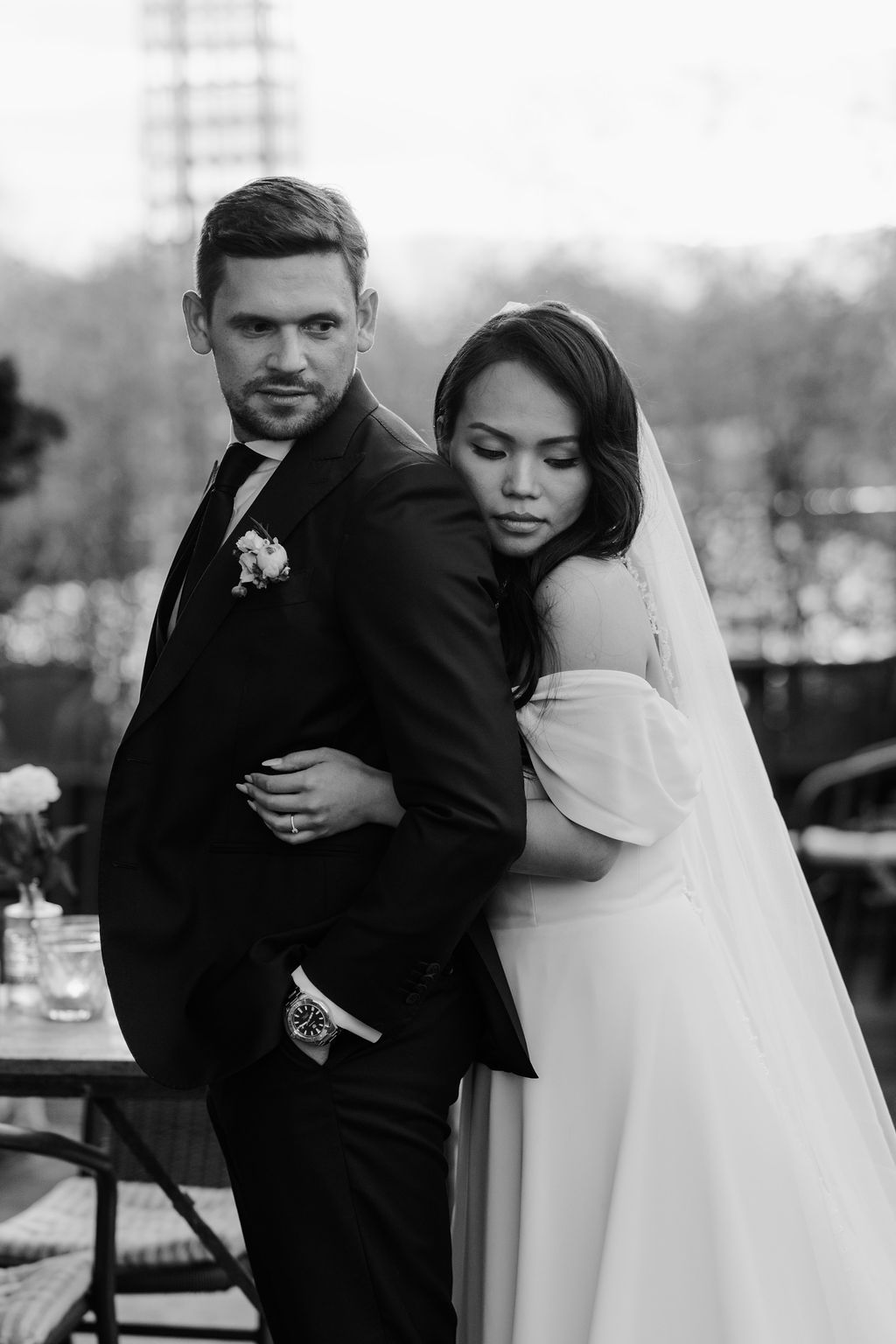 A romantic black and white wedding photo series showing tender moments between a couple embracing outdoors.