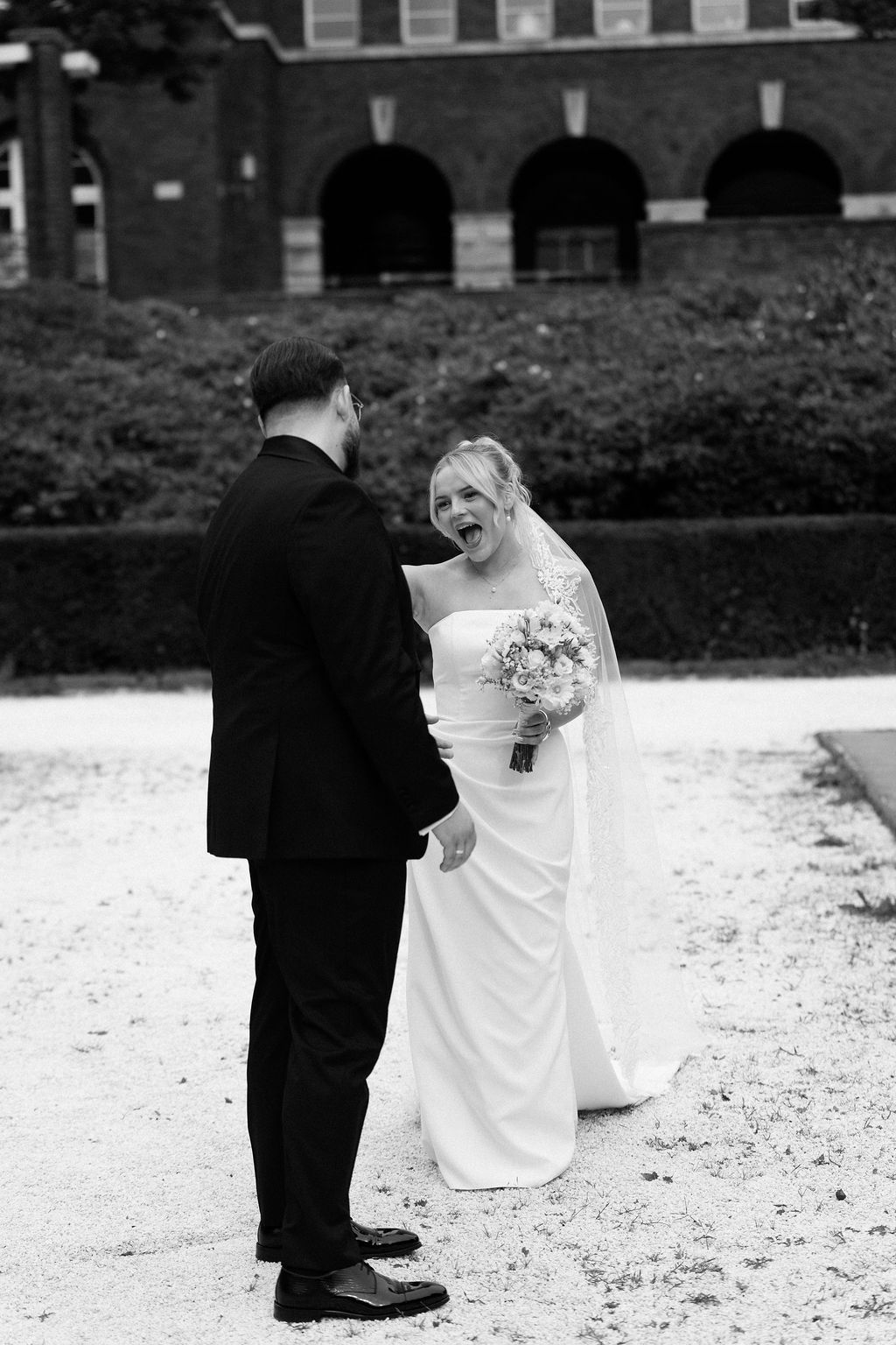 A couple in formal wedding attire poses together in silhouette against a snowy winter landscape.