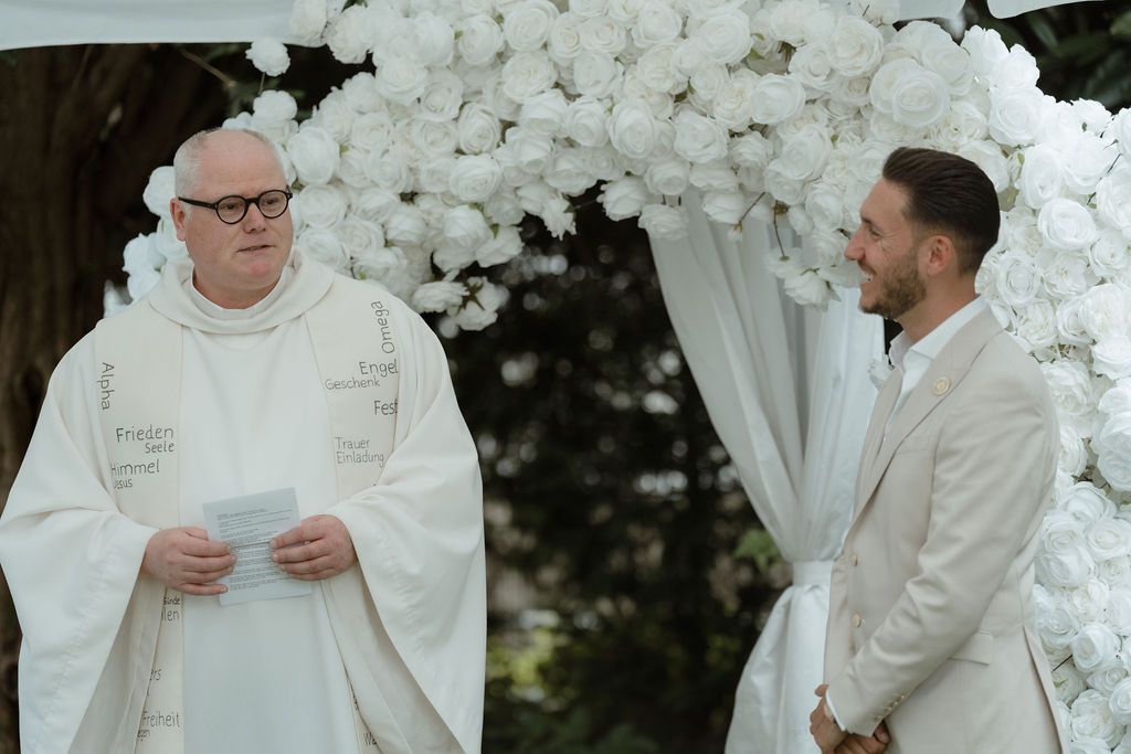 Wedding ceremony moments captured during the vows under white floral decorations.