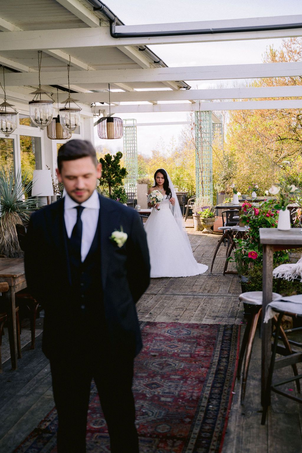Wedding couple photographed on outdoor patio venue with autumn foliage and ornate Persian rugs for decor.