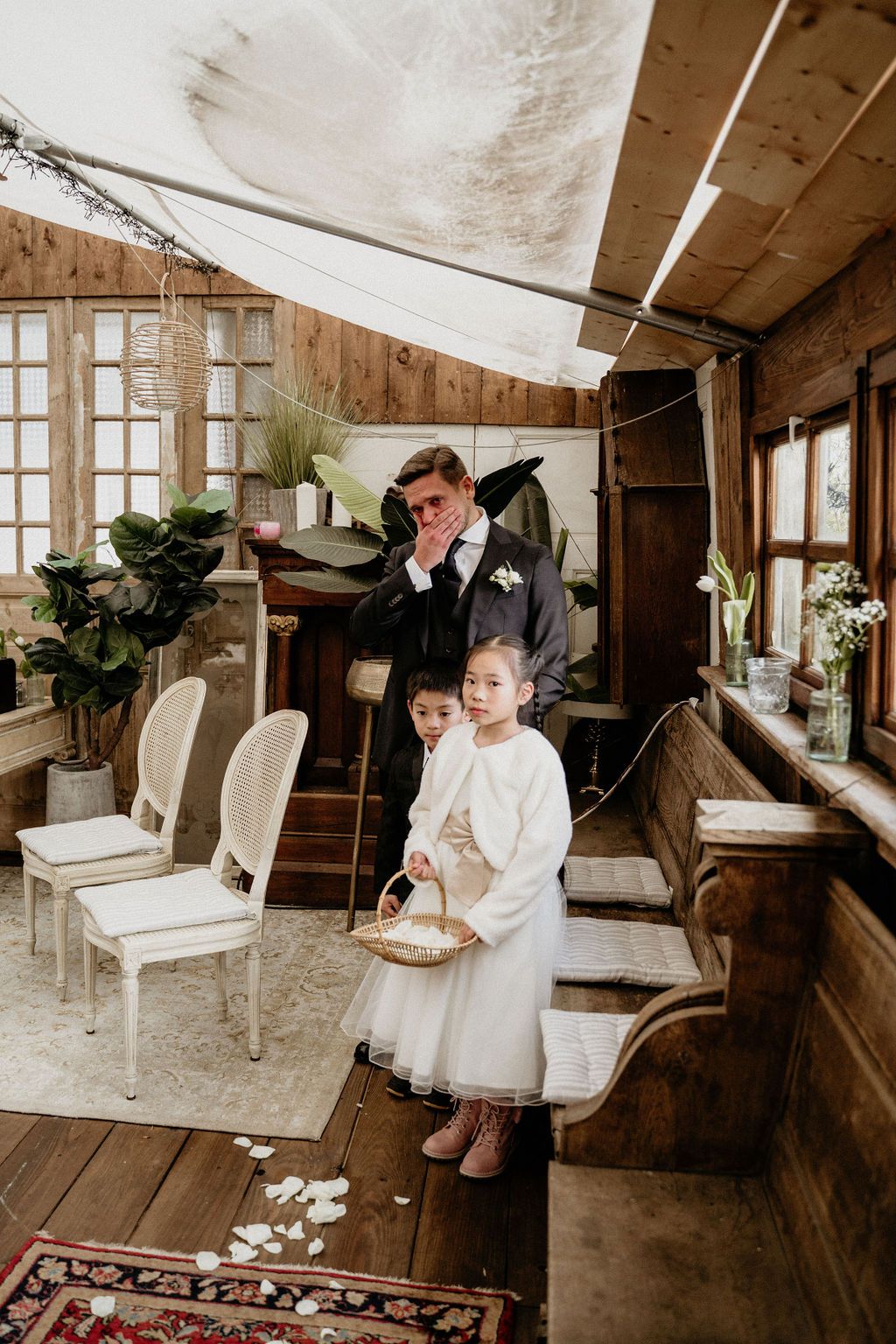 A rustic wedding venue with white chairs, wooden floors, and natural lighting created a charming, intimate atmosphere.