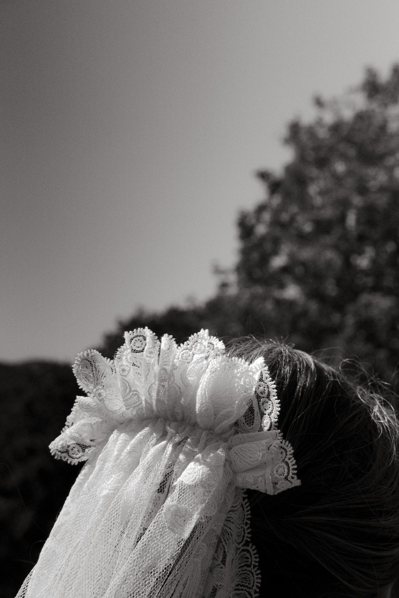 Detailed shot of a white lace veil against a gradient sky background.