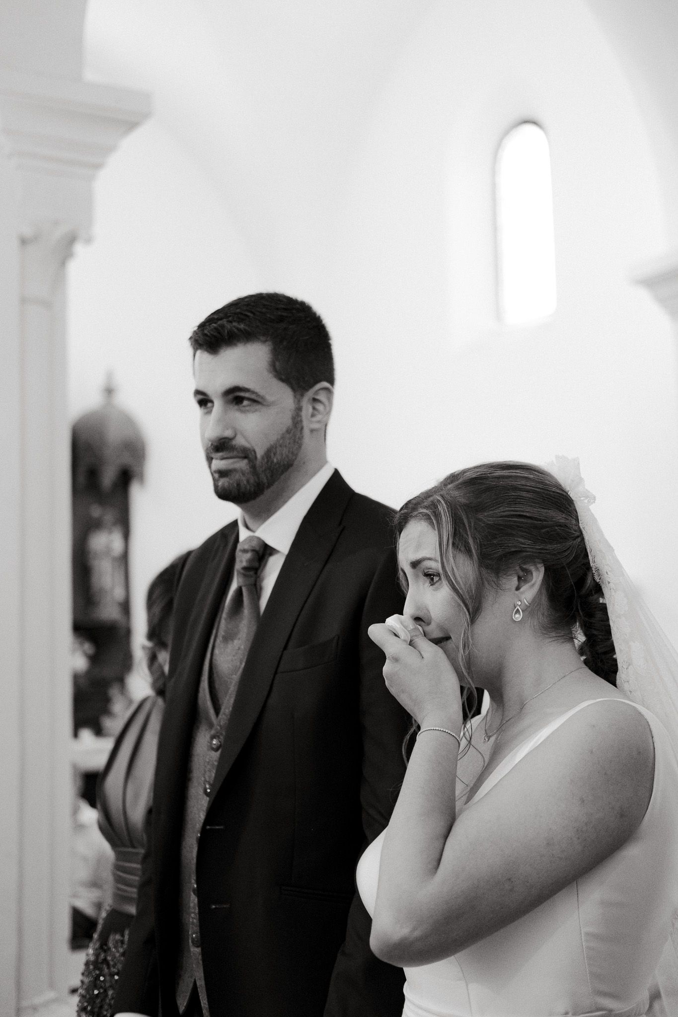 Emotional wedding ceremony moment captured in black and white inside church.