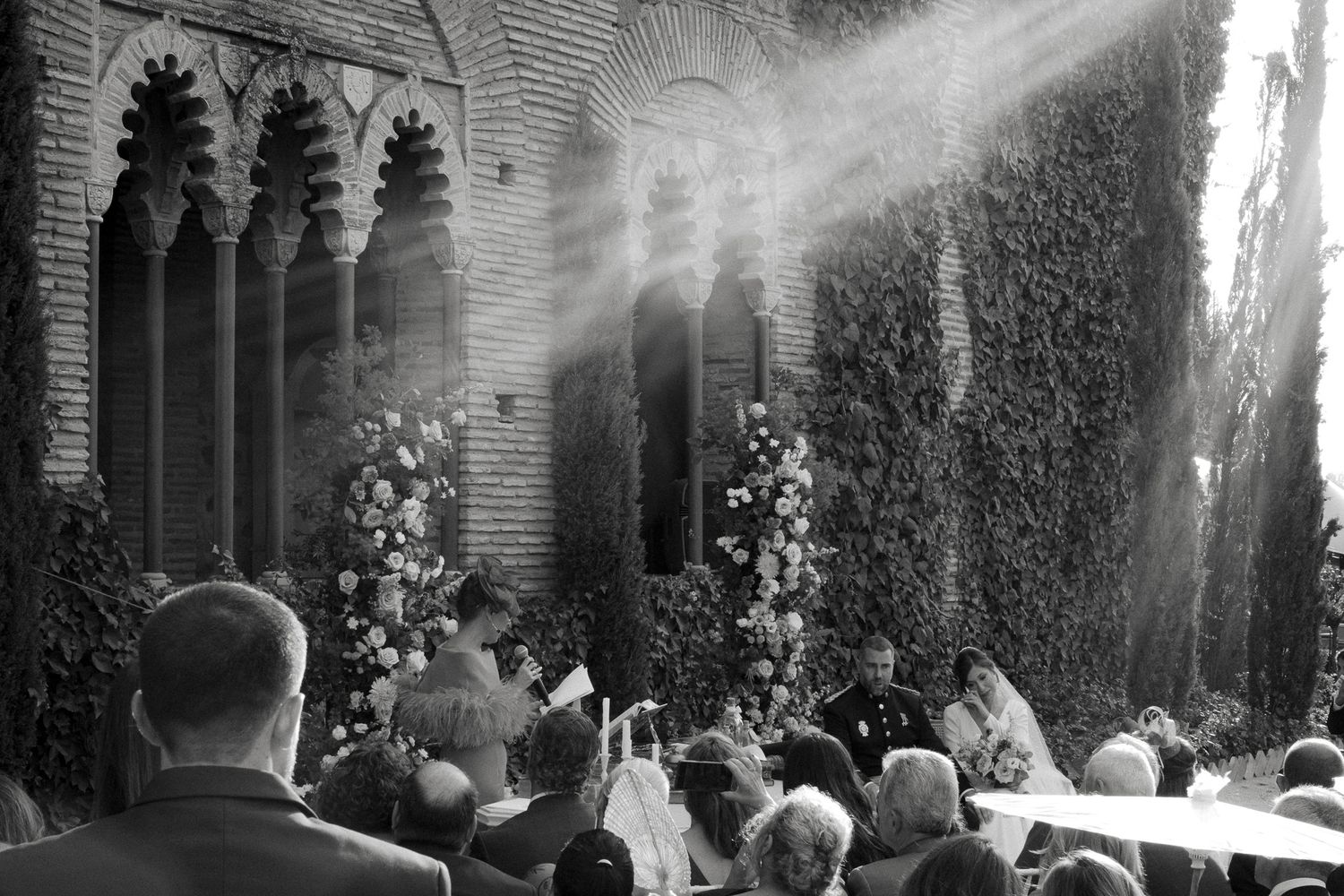 Wedding ceremony in a historic brick venue with sunbeams streaming through arched windows.