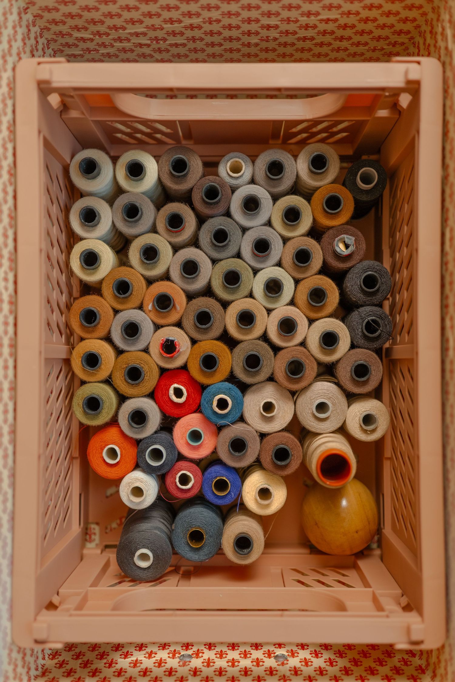 Wooden crates filled with colorful spools of thread in orange, blue, and gray arranged in rows.