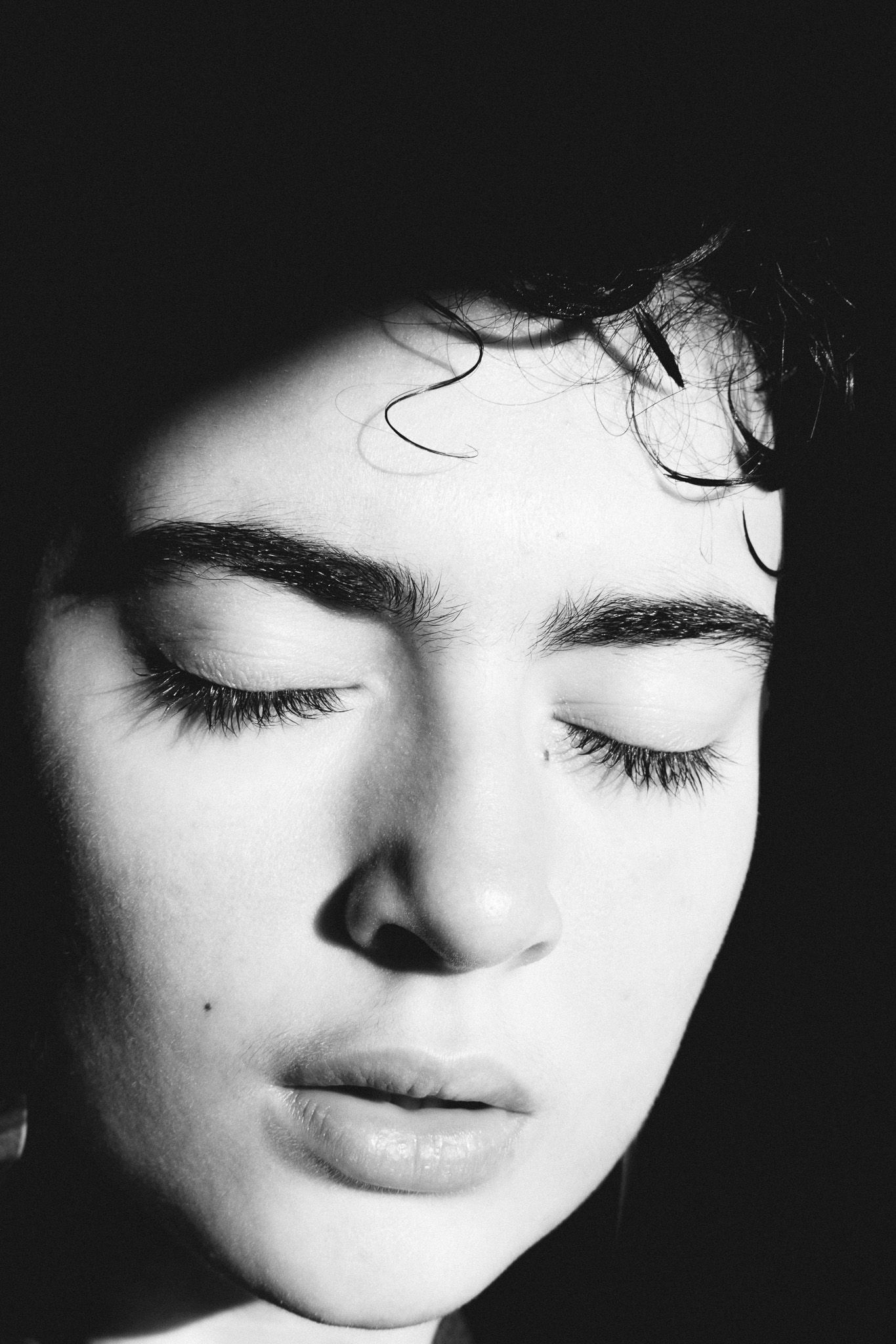 High contrast black and white portrait showing closed eyes and serene expression.