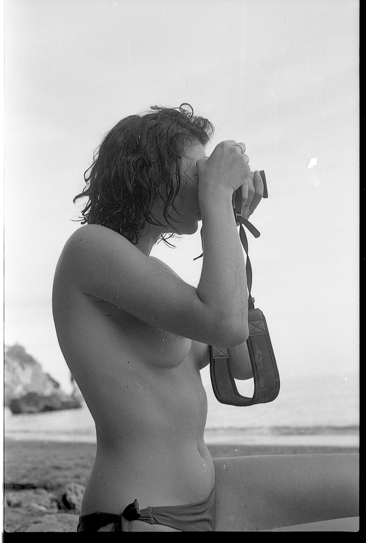 Side profile of a photographer holding a camera against a bright sky.