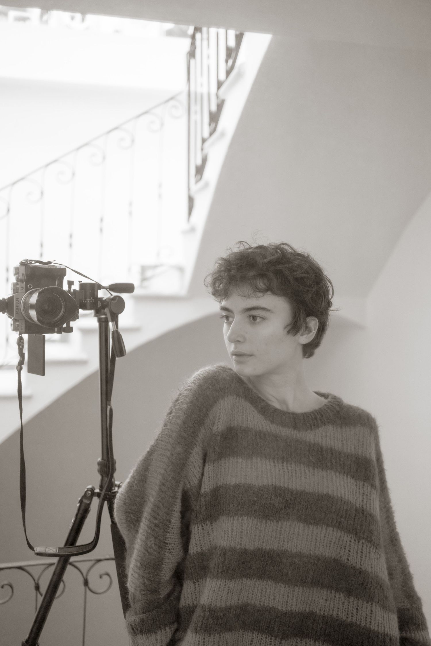 A series of black and white photos showing someone in a striped sweater posing with a camera in different angles.