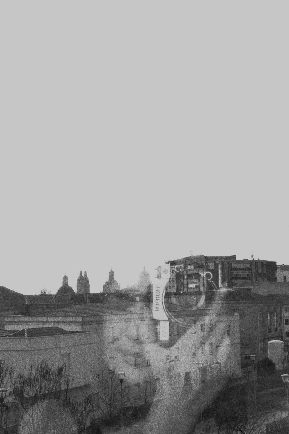 Moody black and white cityscape with church spires visible in the distance.