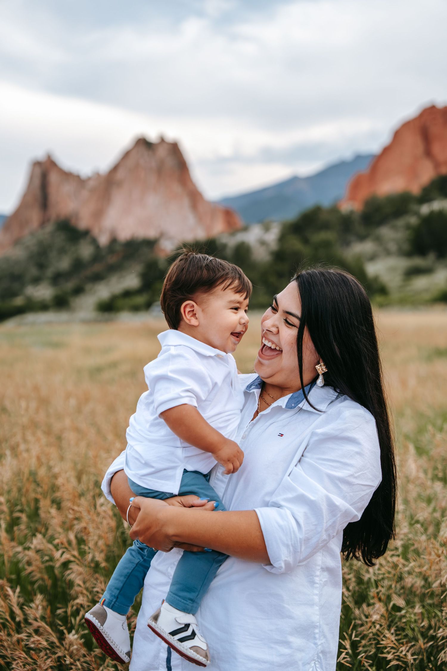 Laughing mother holding joyful toddler in white shirt at Garden of the Gods Colorado.