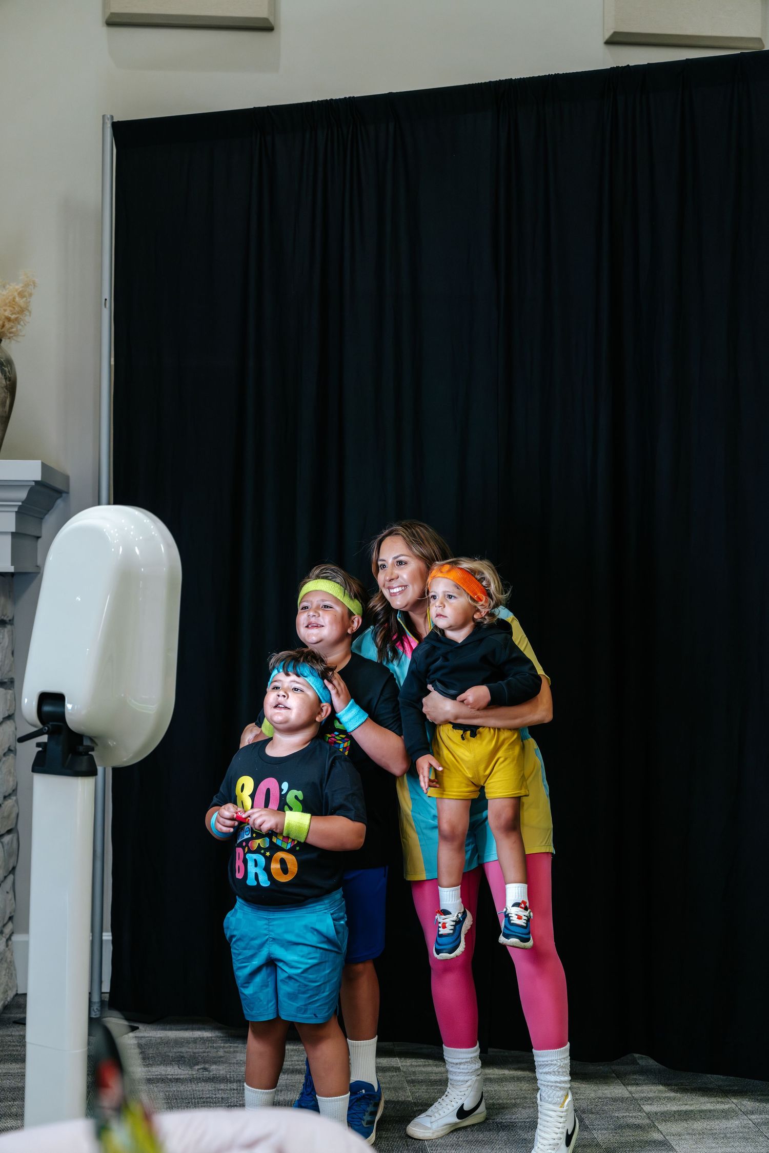 Family dressed in colorful 80s aerobic costumes posing together at a themed photo booth event.