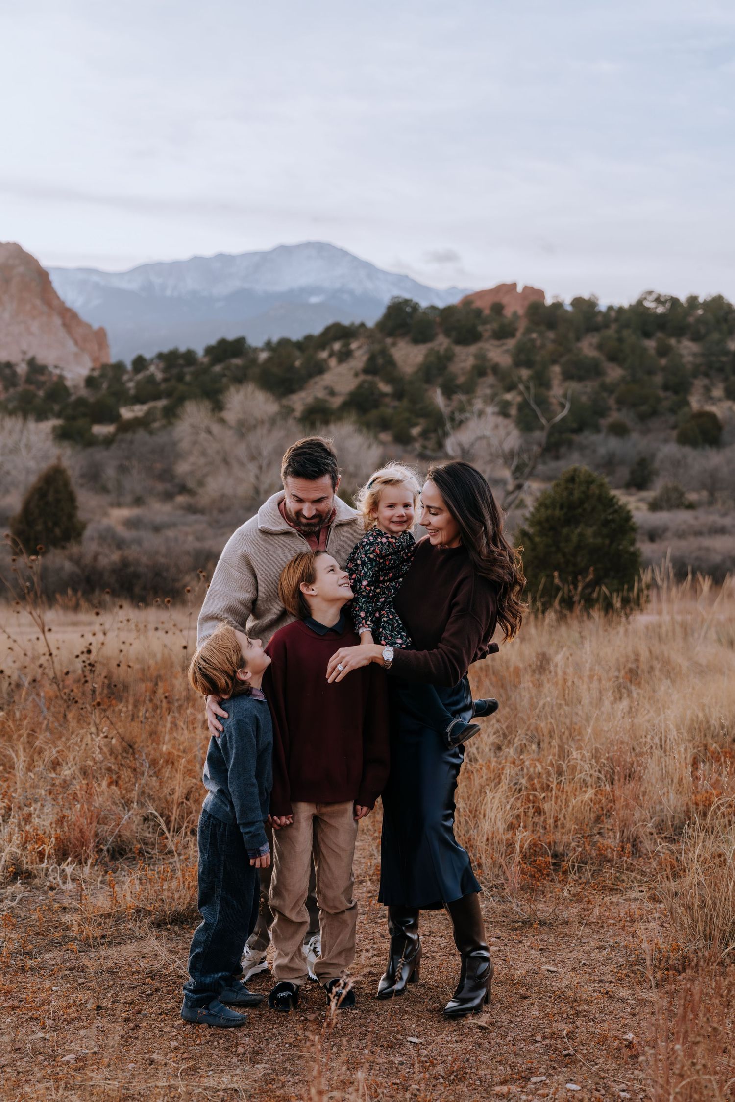 Family of five shares a warm embrace in a mountain field at Garden of the Gods.