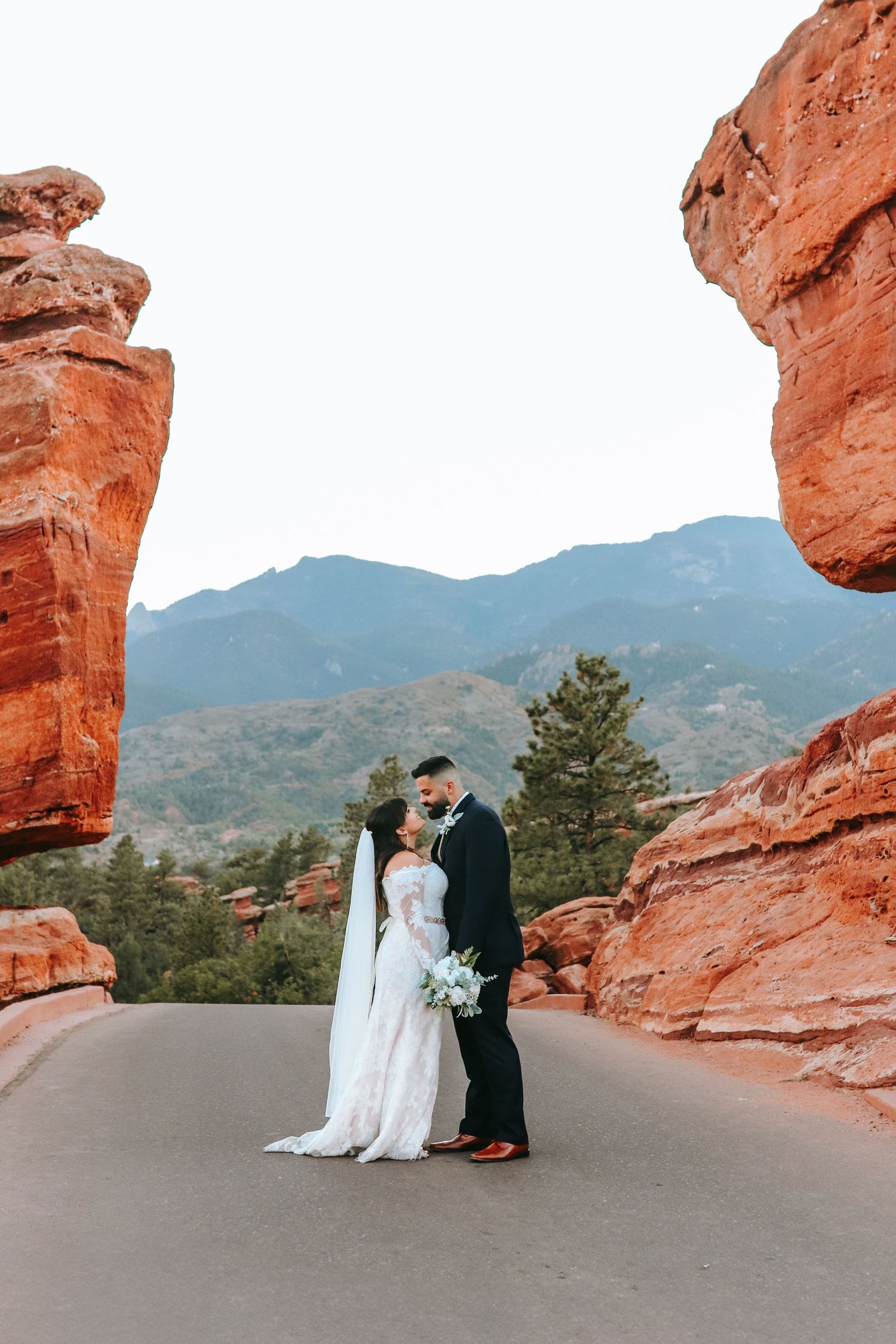 Bride and groom sharing a kiss between red rock formations at Garden of the Gods.