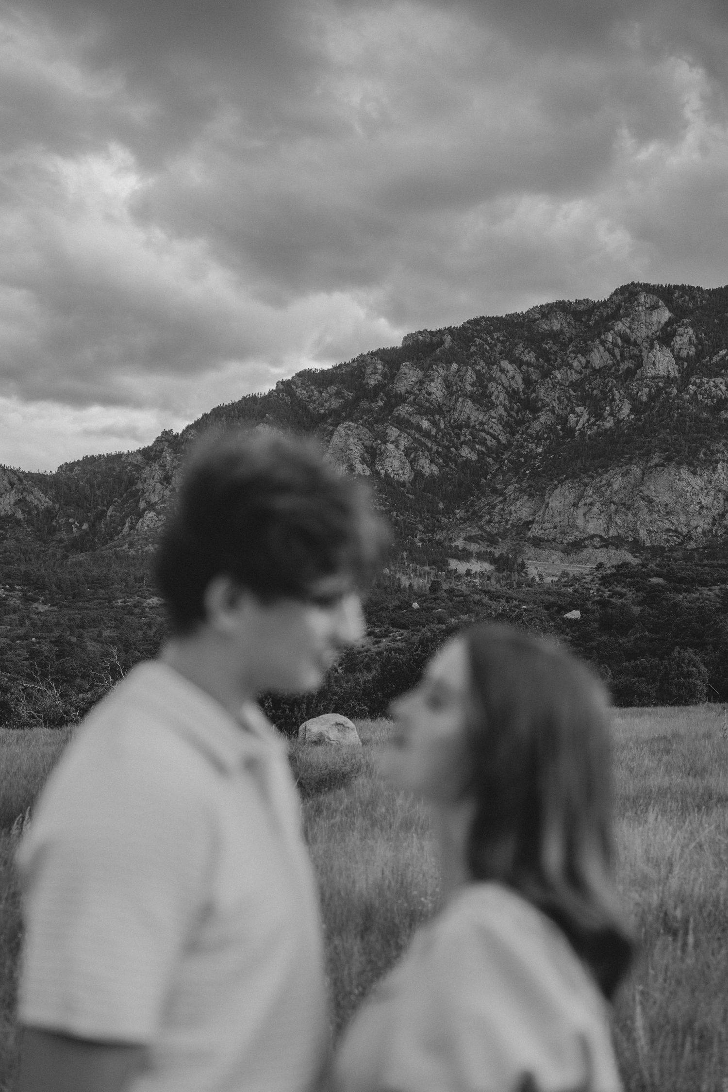Black and white artistic blur of couple about to kiss with dramatic mountain backdrop.