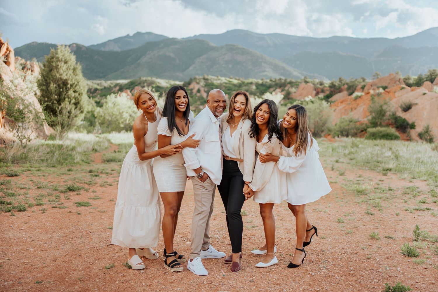 Laughing family of six in white clothing posing at Garden of the Gods Colorado.