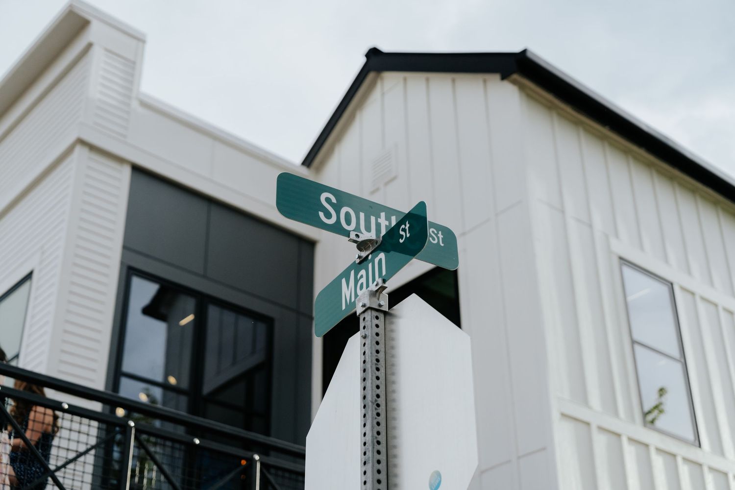 Green street signs at intersection outside modern white barn wedding venue building.