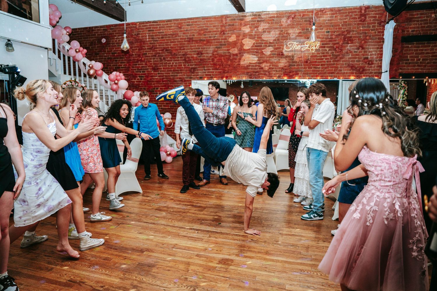 Energetic breakdancer performing for cheering guests on dance floor at quinceañera party.
