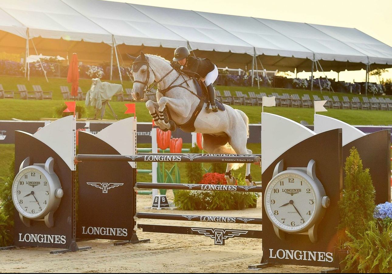 Show jumping competition at sunset with Longines branded jumps and timing equipment.