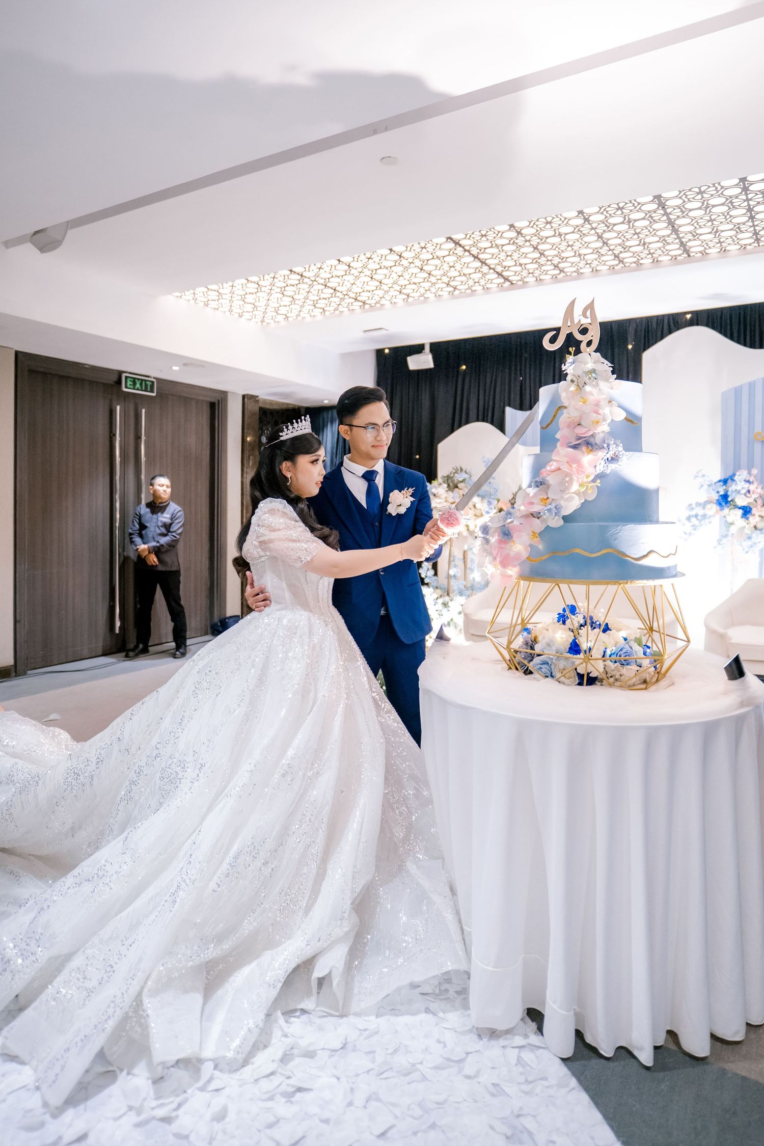 Bride and groom cutting a blue tiered wedding cake at their elegant reception ceremony.