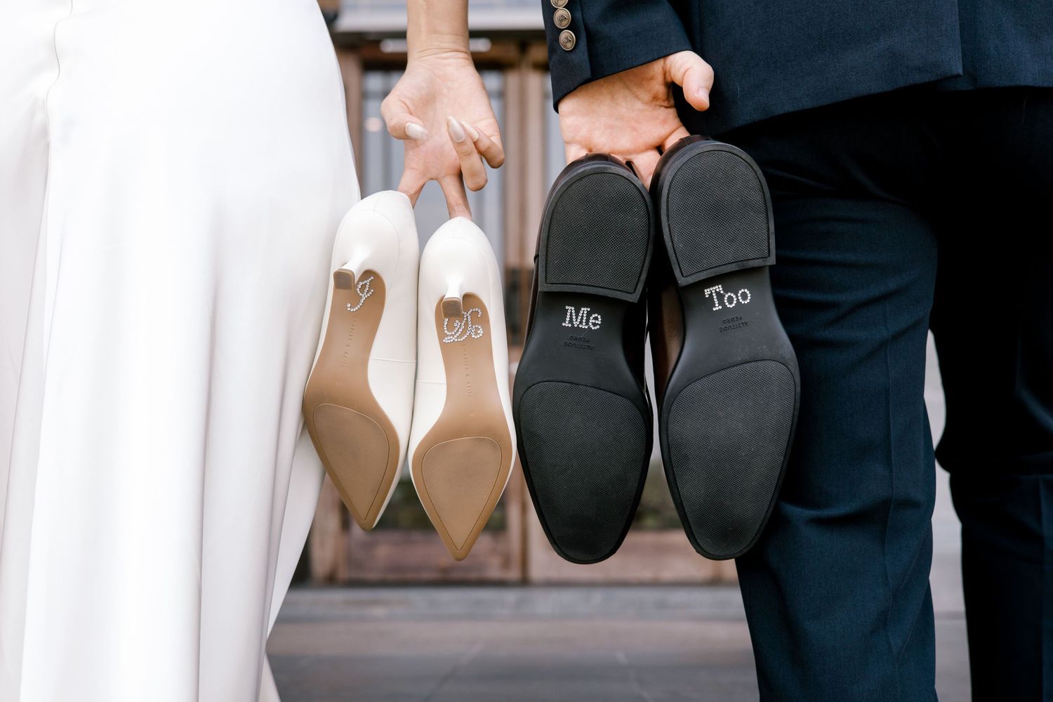 Bride and groom holding up shoes showing Me Too wedding message on soles, romantic couple footwear detail photo.