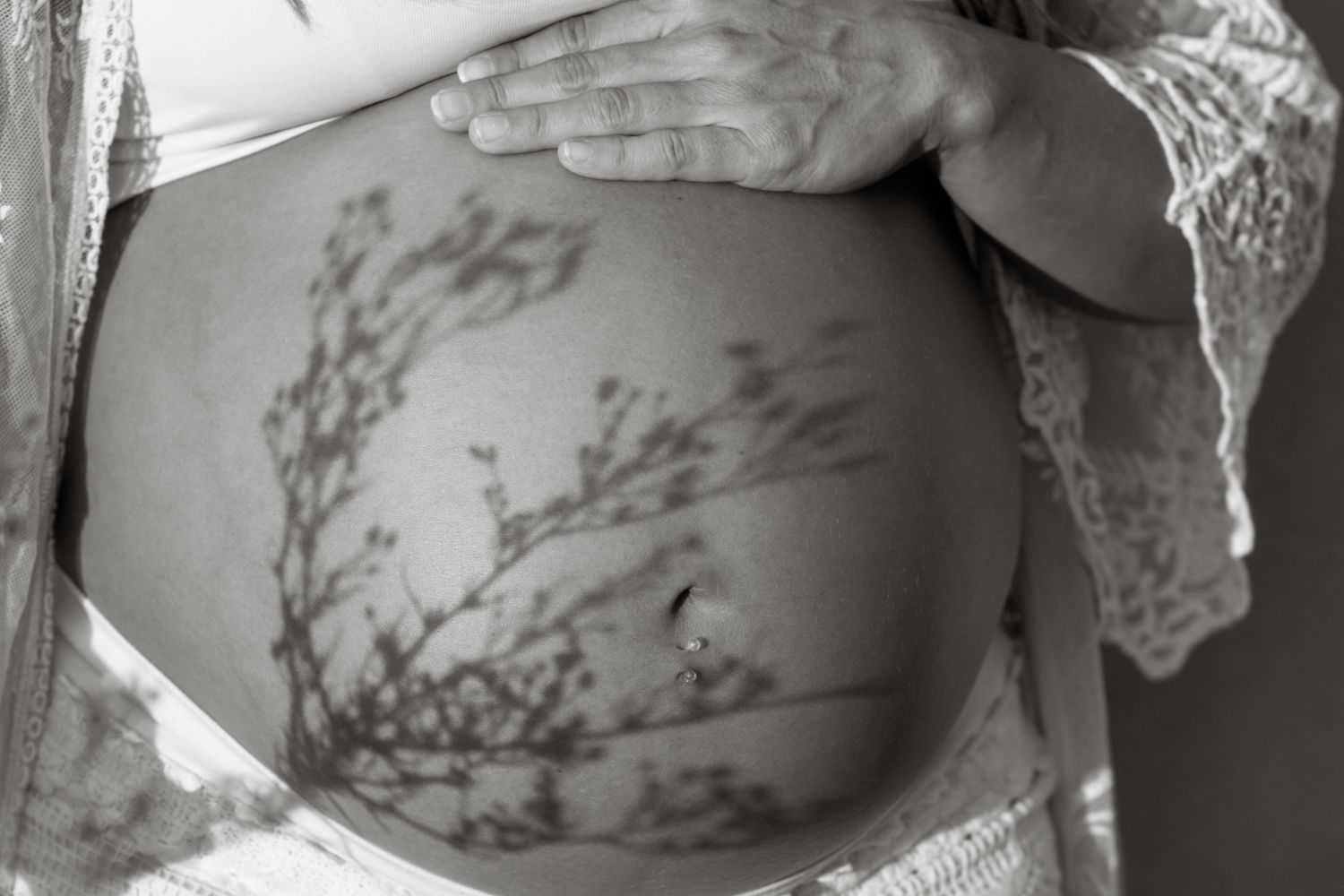 Pregnant mother in flowing dress holding belly during sunset maternity session – Southeast Michigan maternity photographer