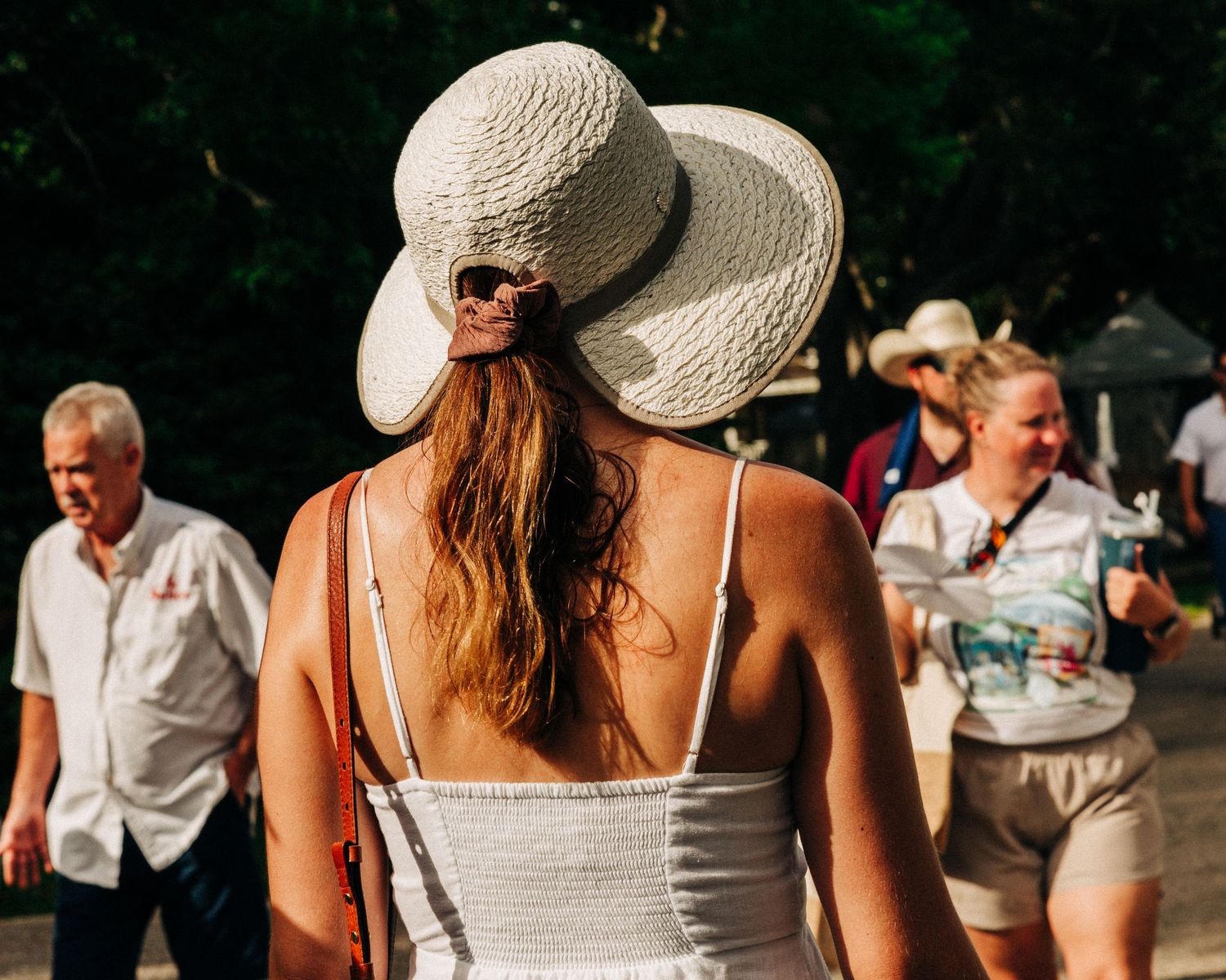 Street photography by Robert Paul | Woman walks in the heat White Linen Festival in League City, Texas, 2025