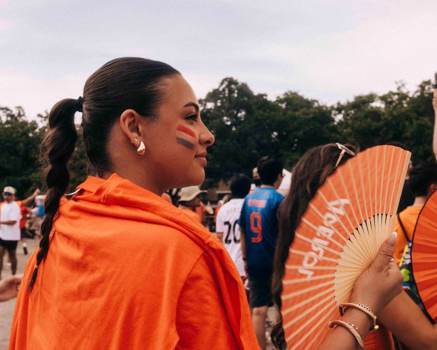 FIFA World Cup 2026 Houston | Fan with face paint fans herself at the beginning of the march Orange Bus fan walk | Photos by Robert Paul