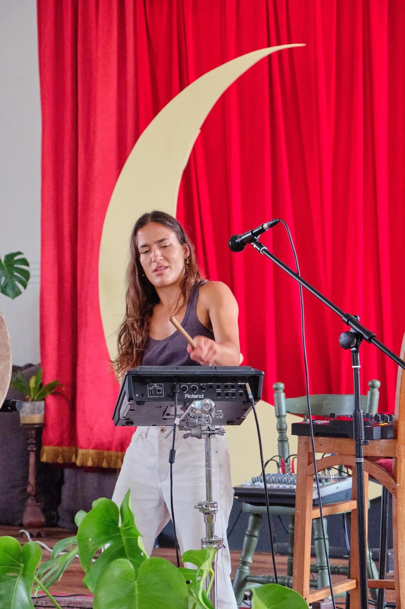 Young woman playing percussion with drumstick at music stand during indoor live performance.