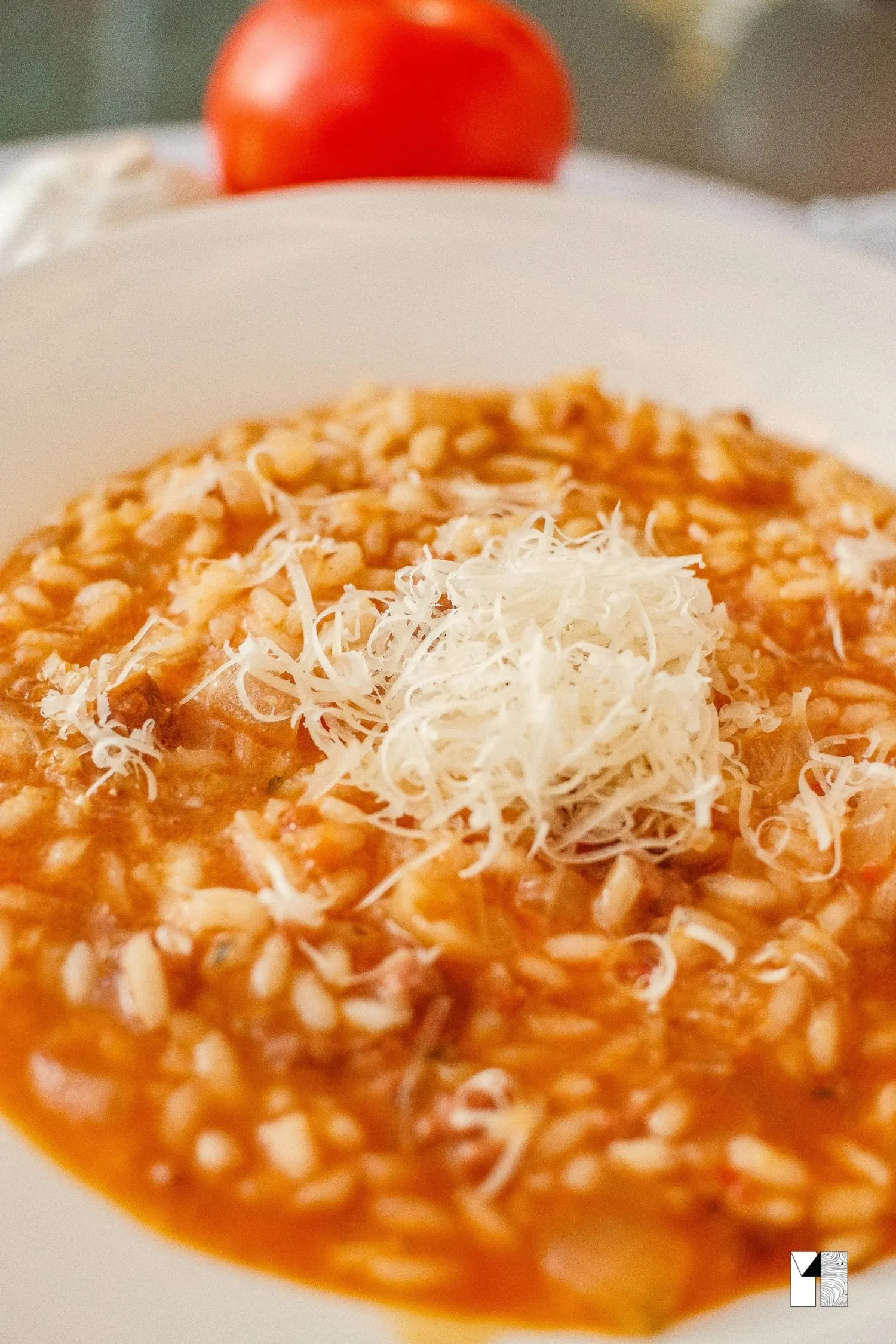Creamy tomato risotto topped with freshly grated Parmesan cheese served in a white bowl.