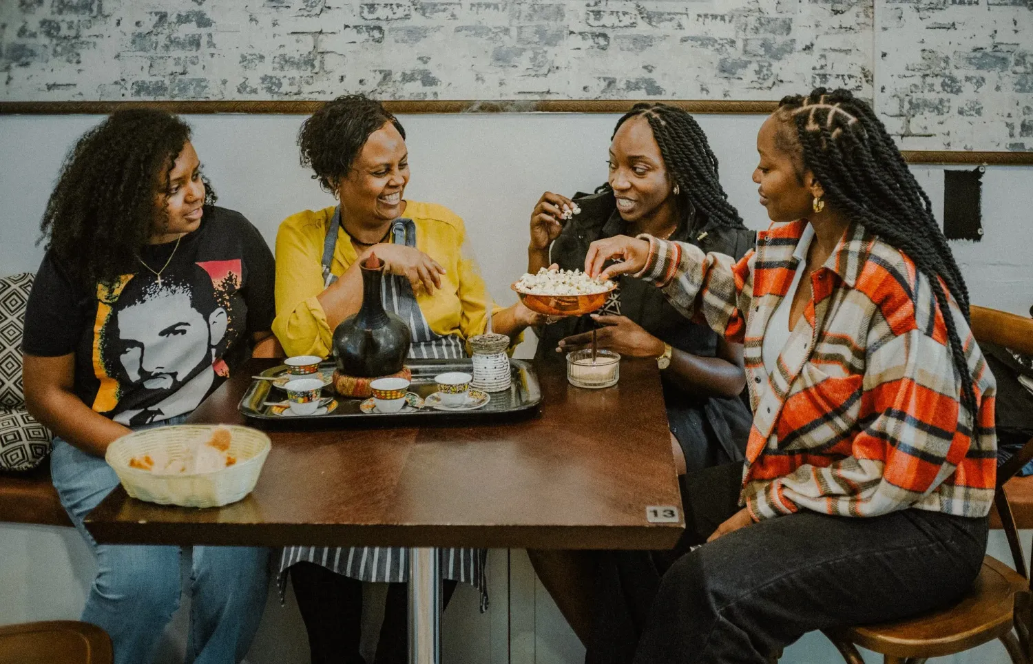 Four women laughing and sharing food together at a restaurant table.