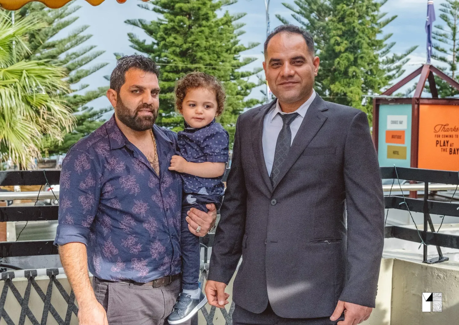 Two men and a young child posing together at an outdoor event.