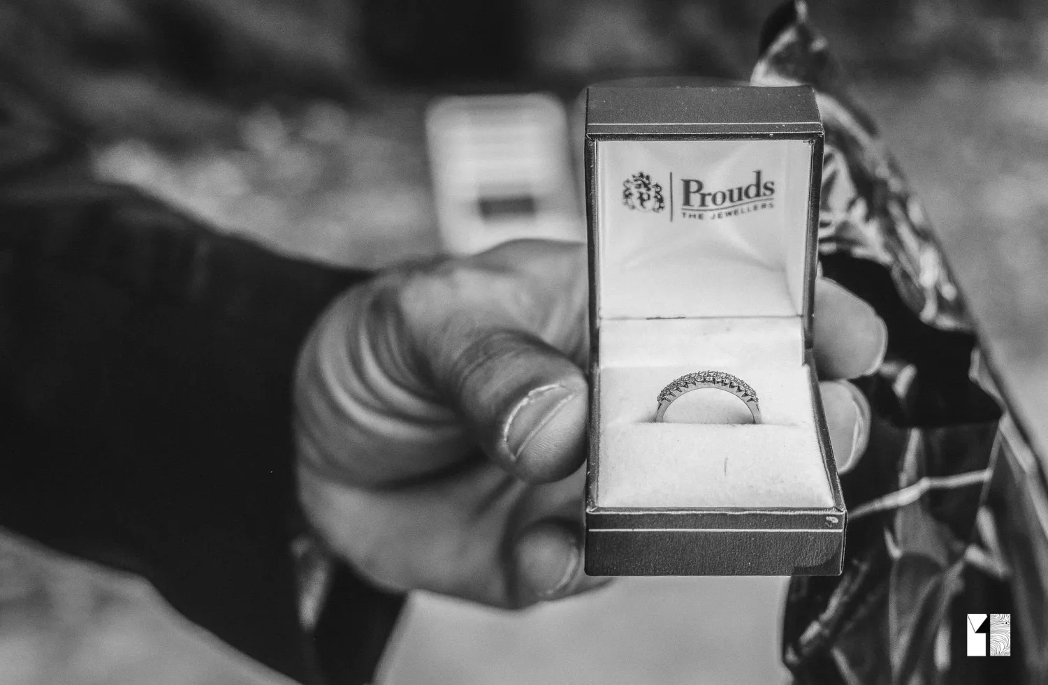 Black and white close-up of diamond wedding band in Prouds jewelry box.