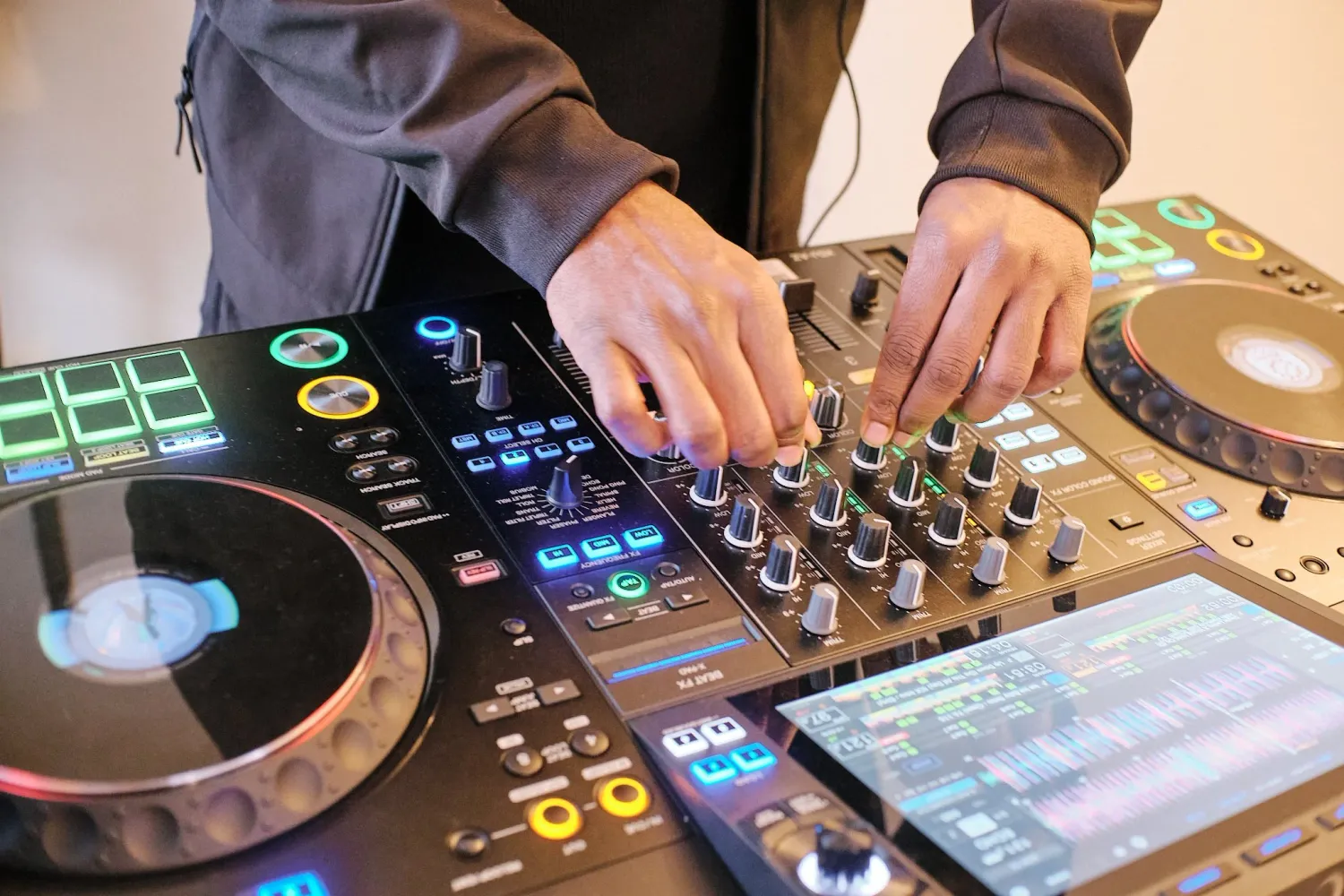 Overhead view of hands mixing music on a professional DJ controller.