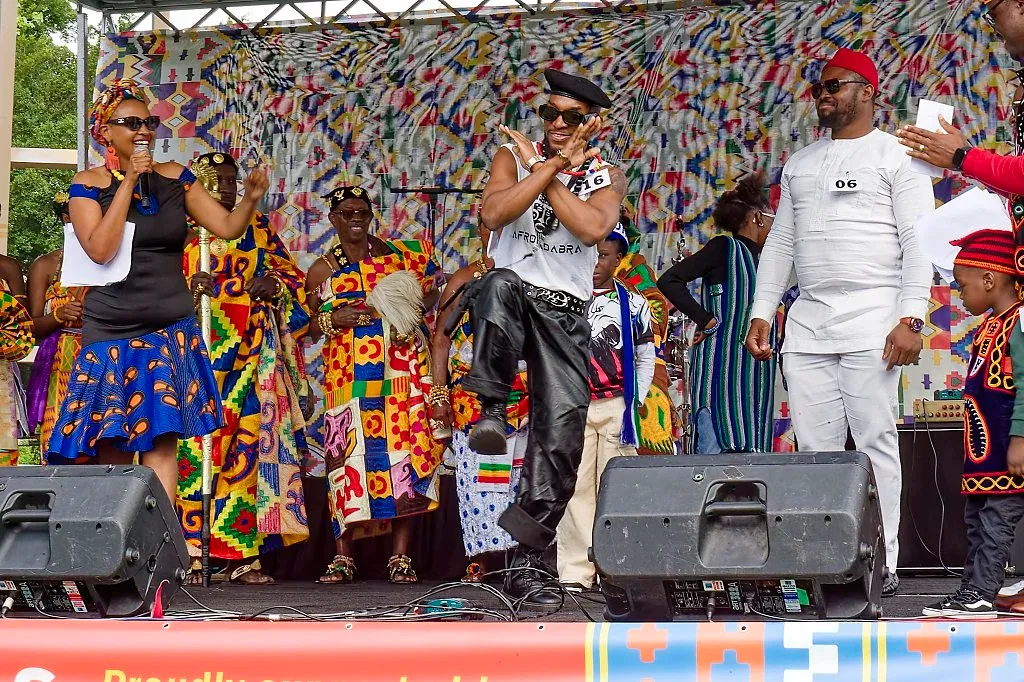Vibrant African cultural festival performance with colorful kente cloth outfits on an outdoor stage.