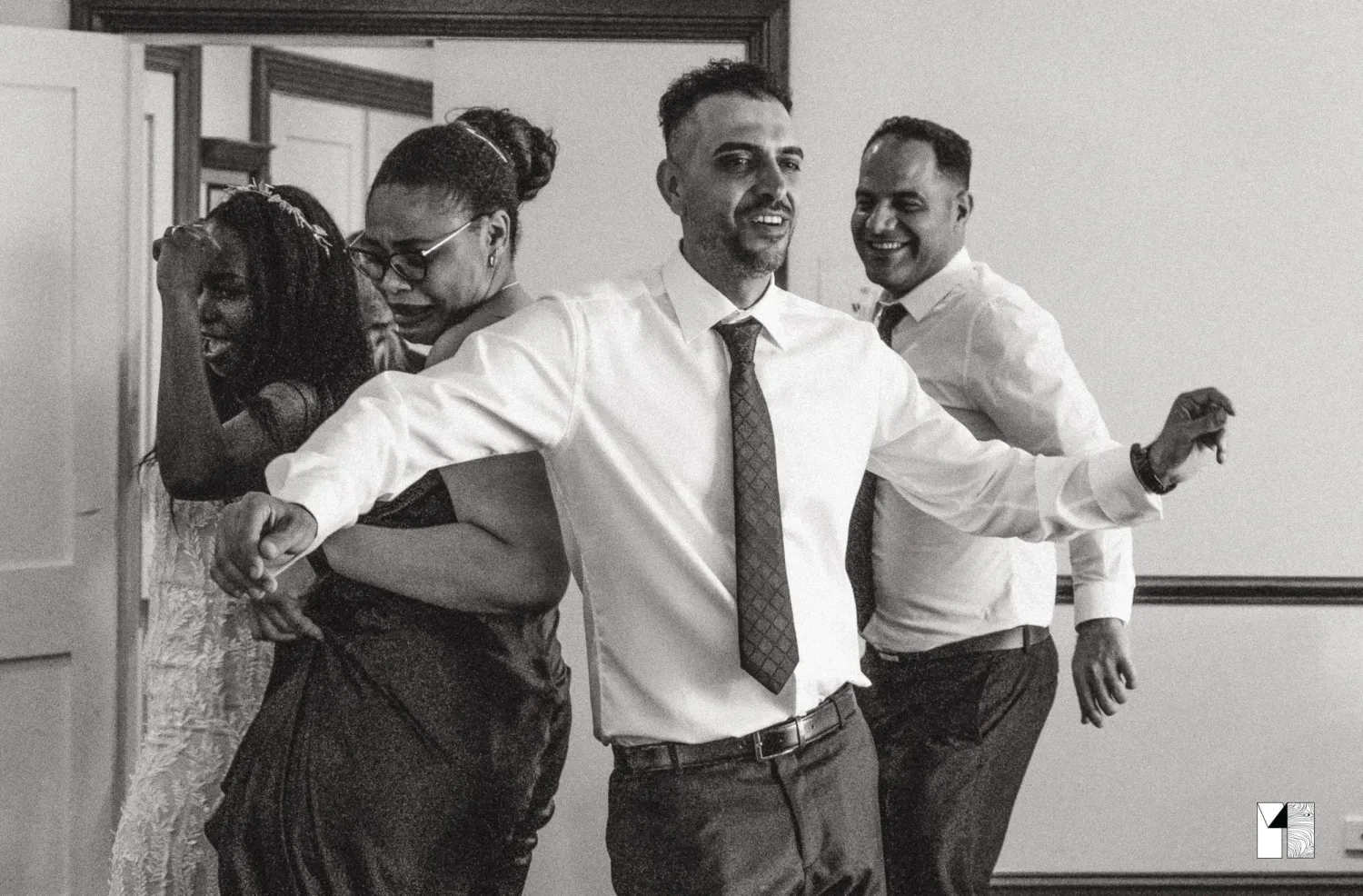 Joyful wedding guests dancing and laughing together at a lively indoor reception celebration.
