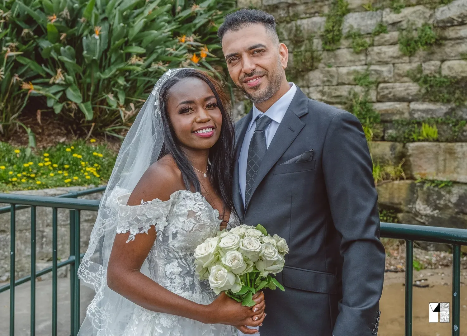 Interracial couple posing together on their wedding day with white roses.