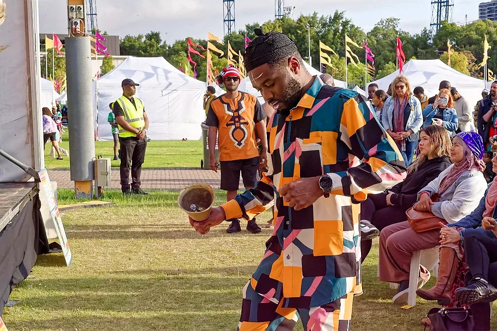 Man in colorful patchwork suit performing at an outdoor cultural festival.