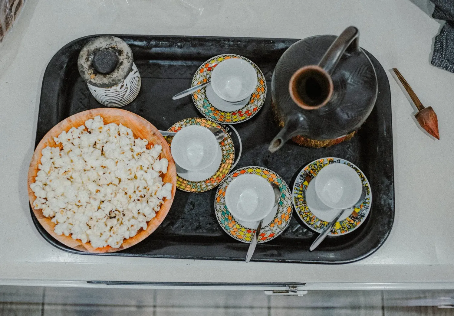 Traditional Ethiopian coffee ceremony tray with ornate cups, jebena pot, and bowl of popcorn.